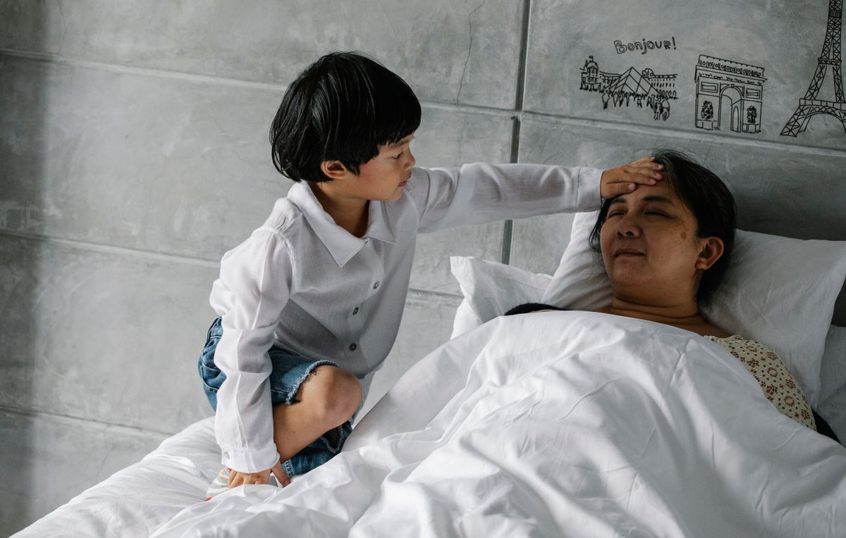 Adult daughter comforting her mother resting in bed at home in Malaysia