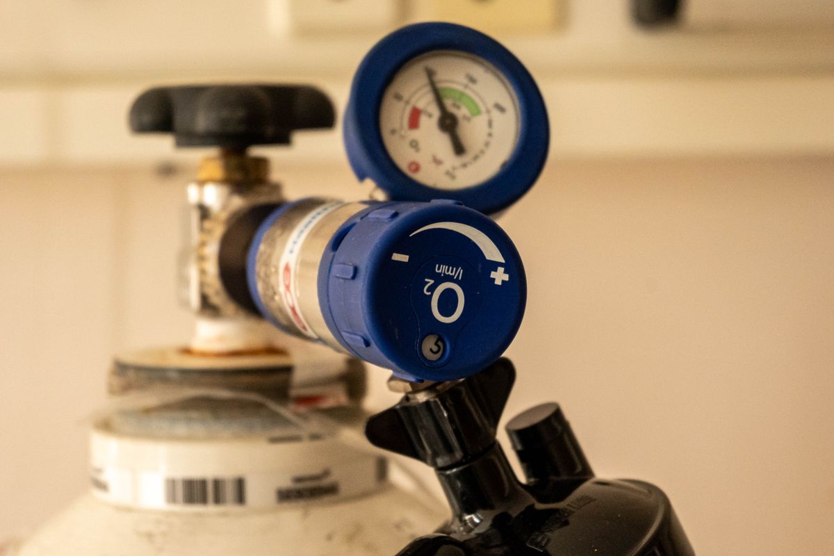 Close-up of an oxygen tank regulator showing the pressure gauge and flow dial