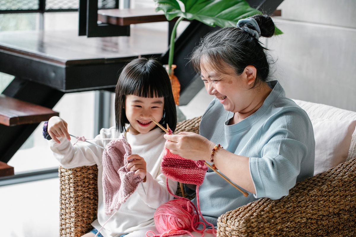 Grandmother and her granddaughter knitting together in the living room