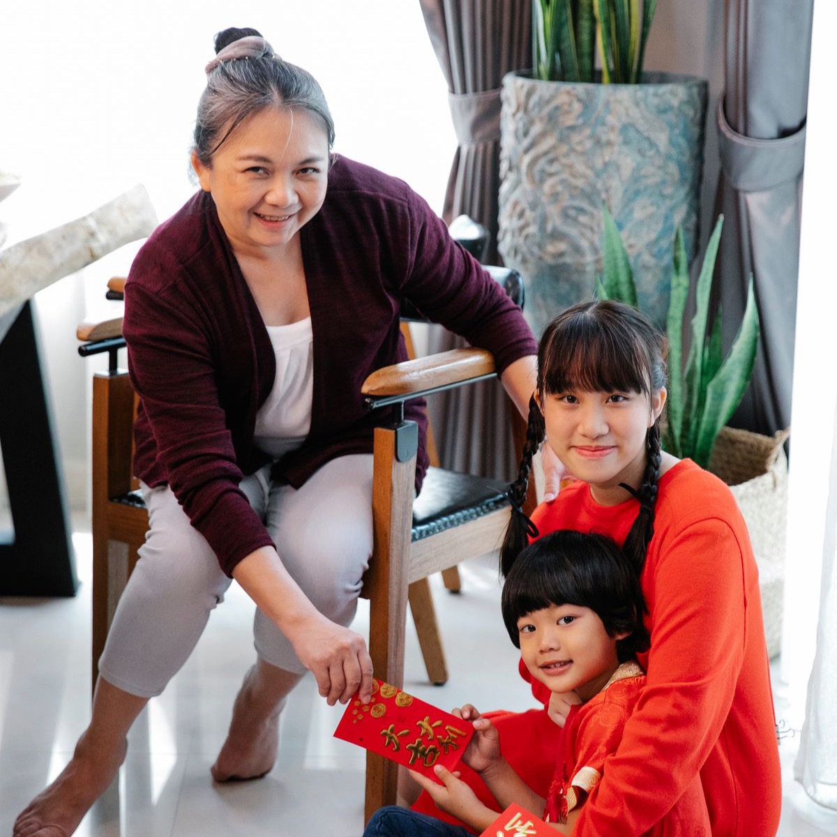 Grandmother handing an ang pow to her grandchildren in the living room