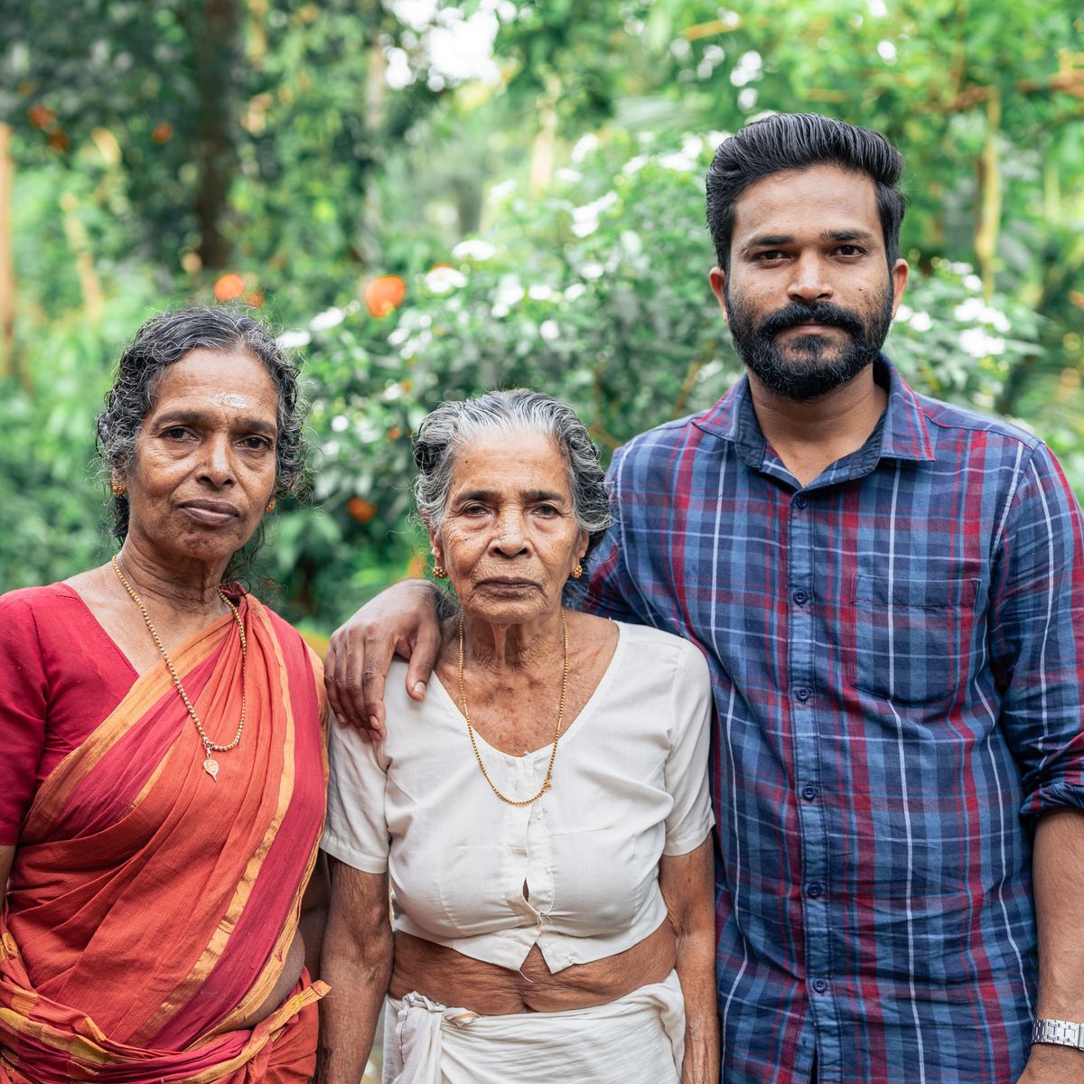 Malaysian Indian family standing with their elderly mother in the garden